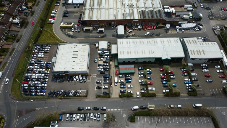 Drone shot capturing an industrial area with parking lots and buildings in Luton, England.